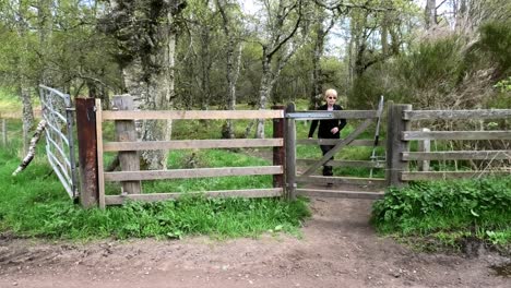 Walker-approaches,-opens-gate,-closes-it-and-crosses-track