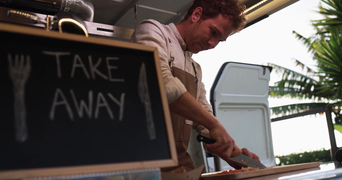 Young Man Chopping Vegetables Inside a Food Truck