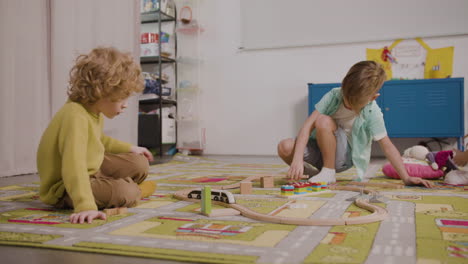 two little boys playing with wooden cars on the carpet in classroom in a montessori school