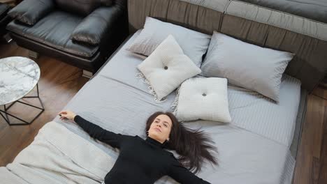woman relaxing on cozy bed with soft pillows in stylish furniture showroom a young woman rests comfortably on a cozy bed surrounded by soft pillows in a bright and modern furniture store