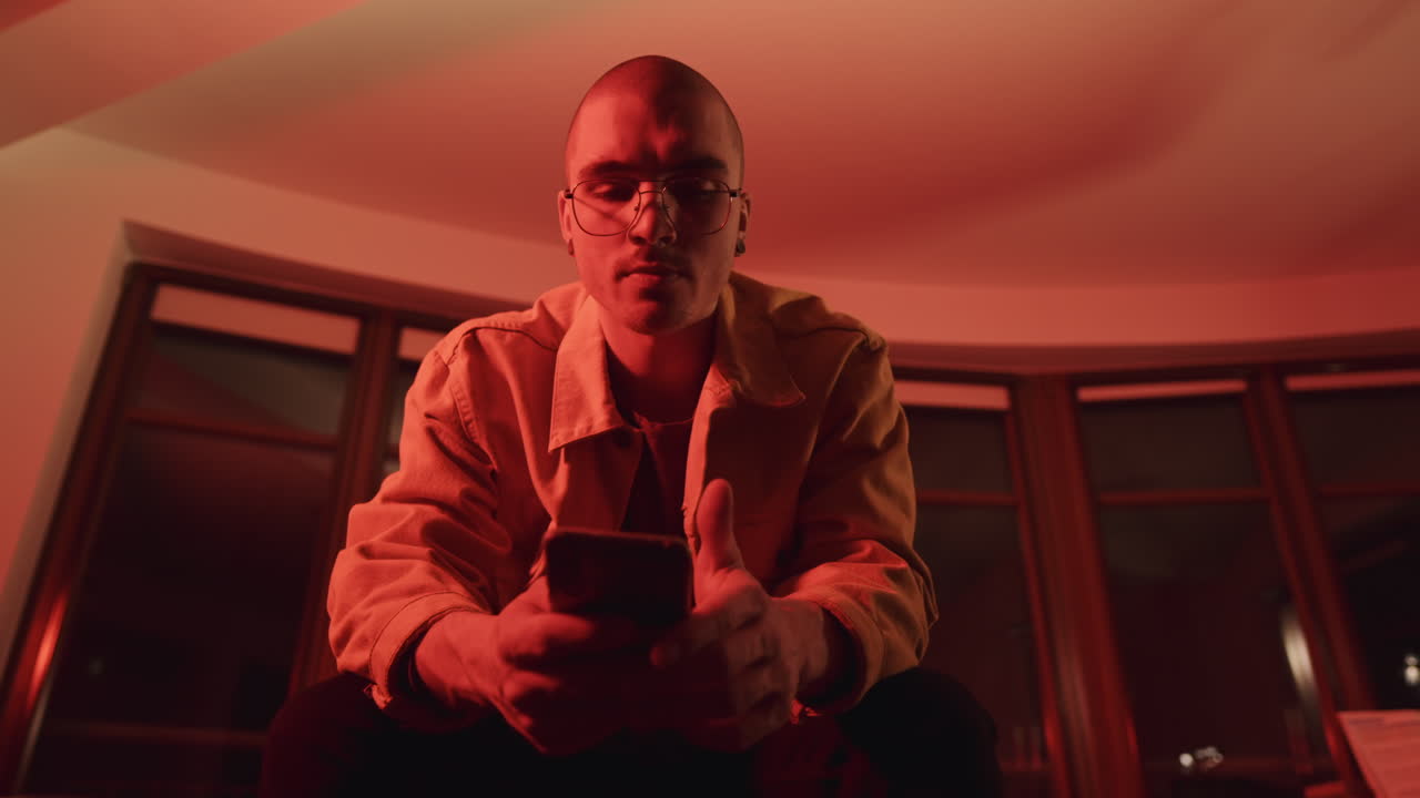 Young man using a smartphone in a dimly lit room