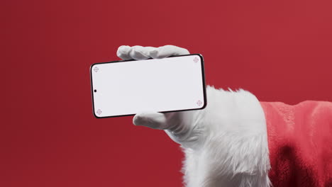 video de santa claus sosteniendo un teléfono inteligente con espacio de copia en fondo rojo
