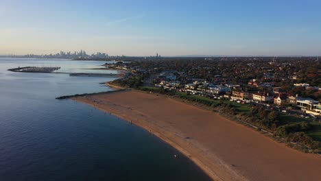 Imágenes-De-Drones-Sobre-La-Playa-De-Brighton,-Con-El-Horizonte-De-Melbourne-En-El-Horizonte-Lejano