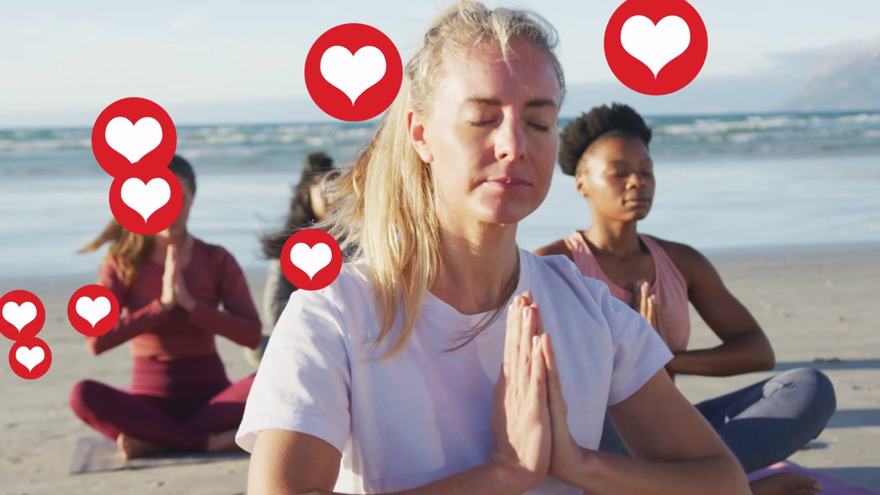 Woman practicing yoga on beach pressing palms at chest while hearts emerging from left showing love