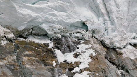 water flowing from the bottom of adishi glacier in svaneti region in georgia - aerial pull back shot