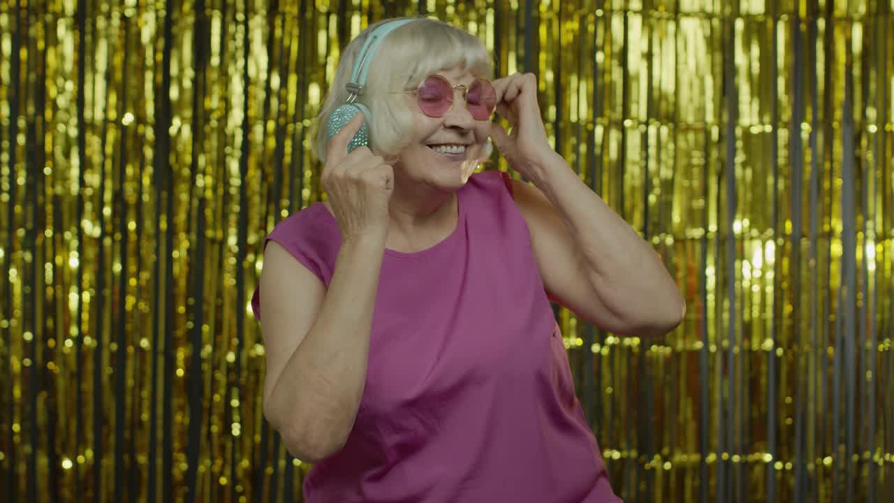 una anciana senior baila, escucha música en los auriculares, se relaja, disfruta, se divierte, sonríe.