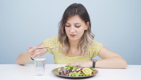 persona que mira las verduras en el tenedor con una expresión infeliz. dificultad para hacer dieta.