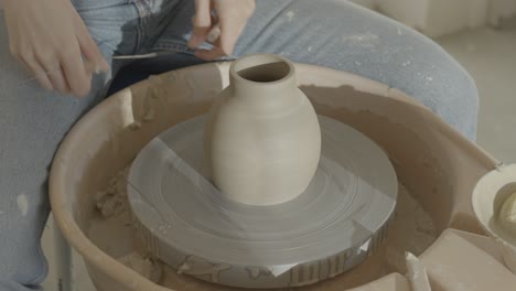 a female ceramicist removing a vase from the wheel