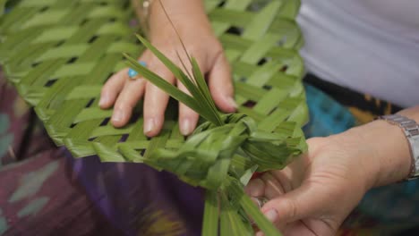 primer plano de una mujer tejiendo una planta en una forma tradicional maorí en nueva zelanda