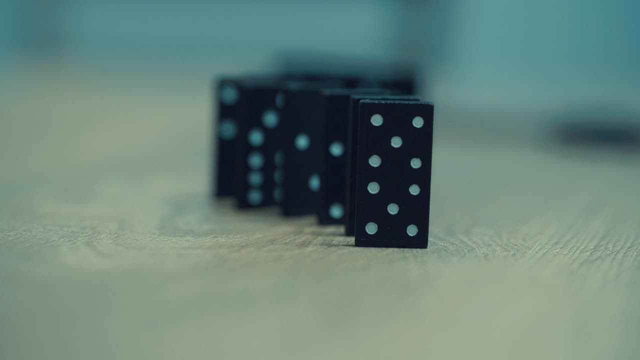 mano femenina de una mujer, vestida con un traje de negocios blanco destruyendo bloques de dominó, que están cayendo