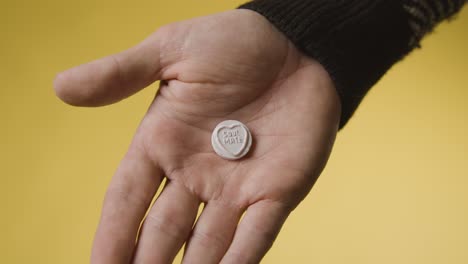 close up of hand holding heart candy with soul mate message on yellow background