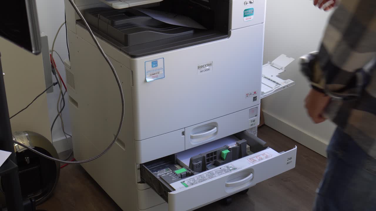 사무실 배경 에 맞춰 사무실 의 복사기 에 종이 를 재고 하는 사람