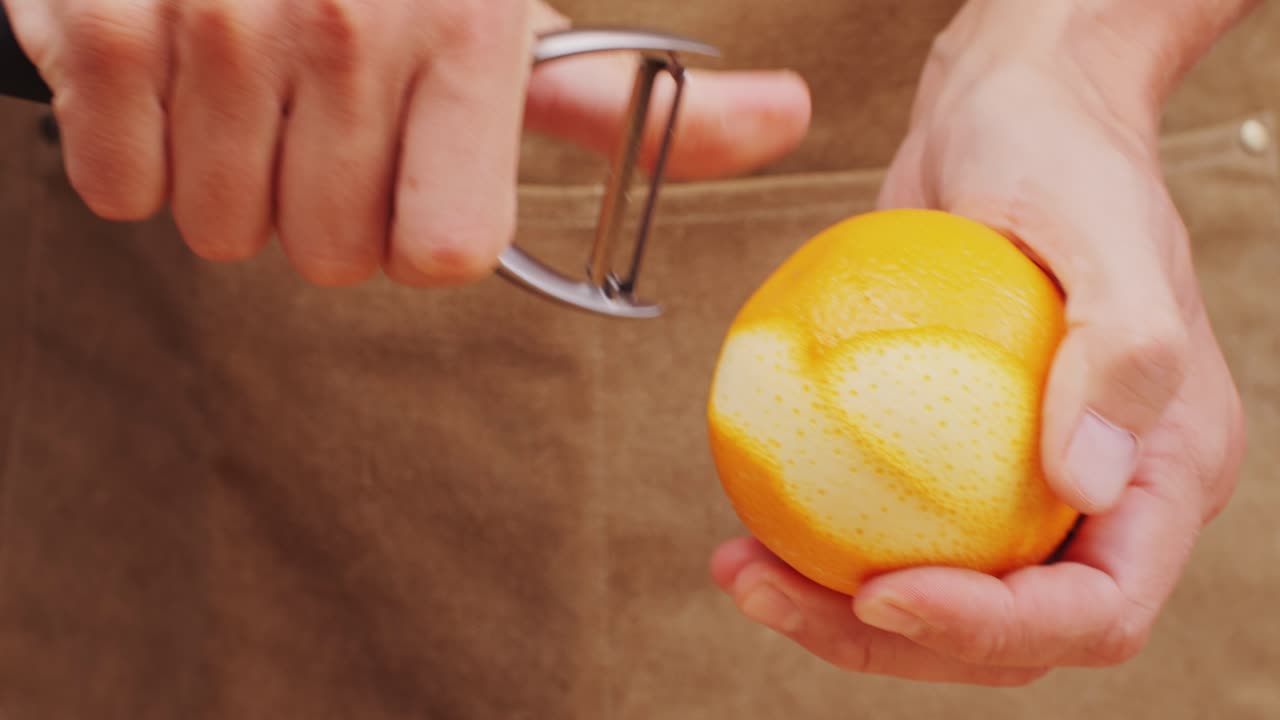Barman prepara un cóctel en un vaso con cáscara de naranja. Metraje 4K de alta calidad