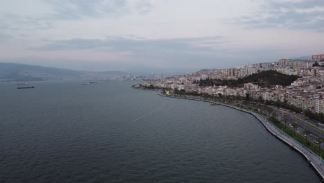 Luftdrohnenvideo-Von-Göztepe-Izmir-Mit-Berg,-Ägäisches-Meer-Im-Hintergrund-Bei-Sonnenuntergang-Mit-Verkehrsfluss