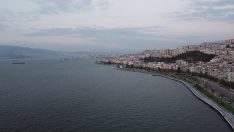 video aéreo de drones de goztepe izmir con montaña, mar egeo en el fondo al atardecer con flujo de tráfico