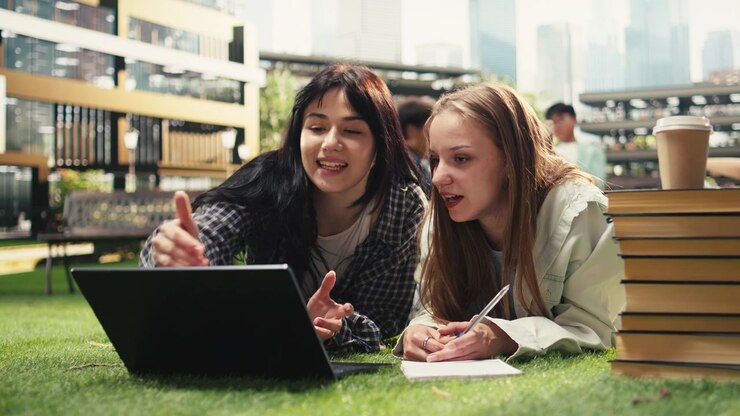 Studenti sdraiati e chinati su un laptop aperto e materiali di studio
