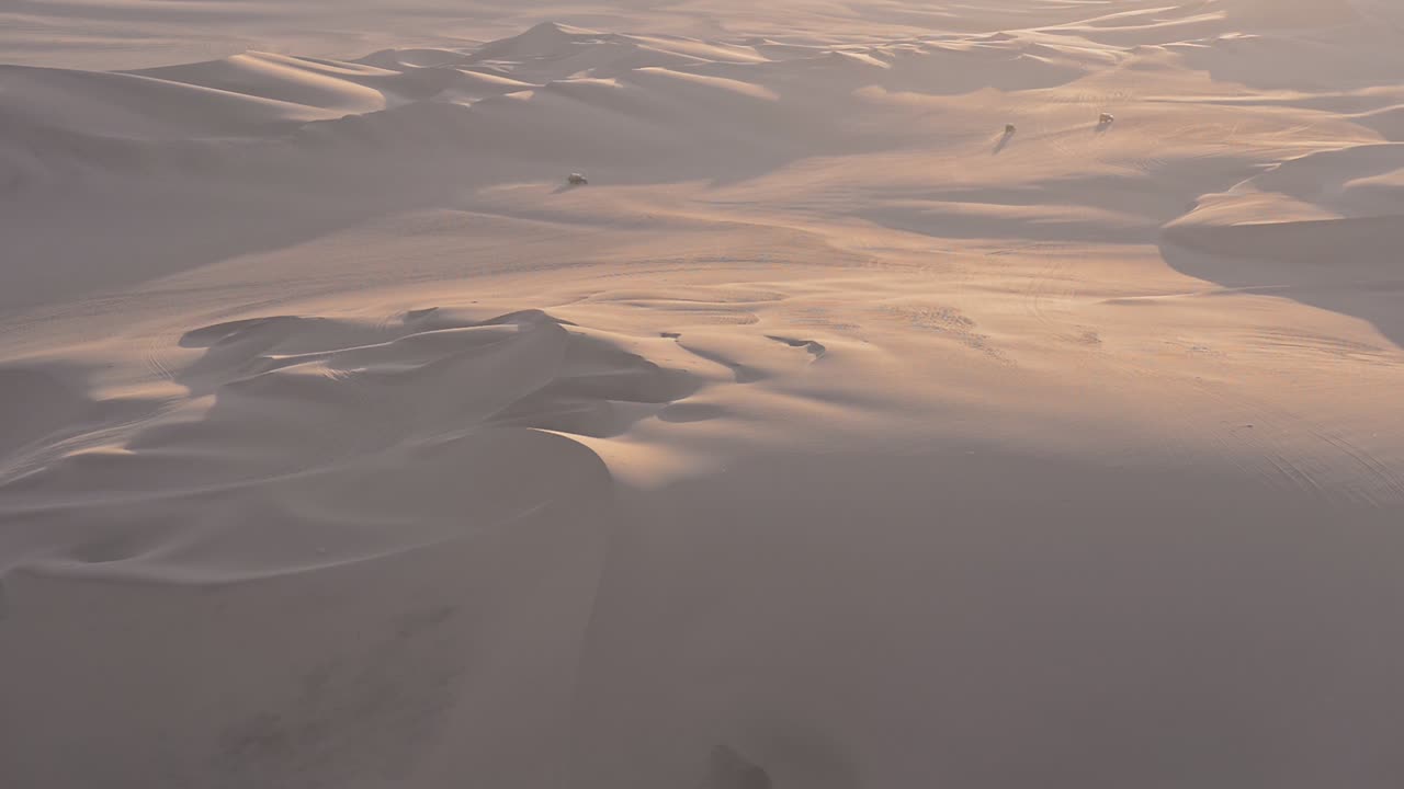 Peruvian desert landscape view with quad speeding on distant dunes, at dusk