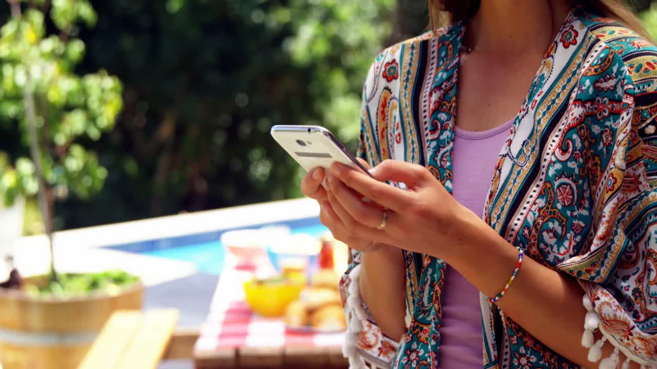 niña usando teléfono móvil cerca de la piscina