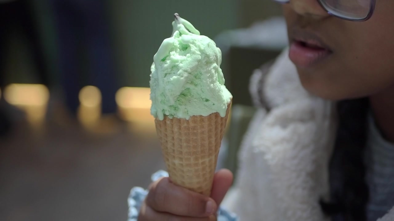 Giovane che gusta una pallina di gelato alla menta in un cono waffle