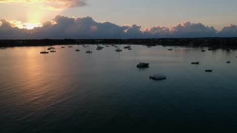 A-wide-aerial-shot-of-a-bay-with-many-sportboats-anchored-at-sunrise