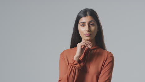 Studio-Portrait-Of-Serious-Young-Businesswoman-Resting-Face-On-Hand-Against-Plain-Background