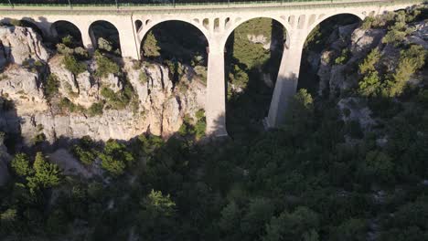 drone shot of the bridge built over the giant canyon formed between two large mountains, forest view