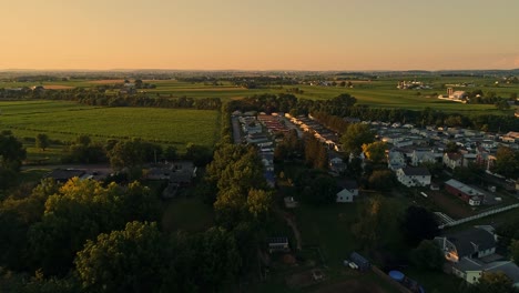 una vista aérea de granjas y campos amish y un parque de casas móviles, manufacturadas y modulares durante la hora dorada en una tarde de finales de verano