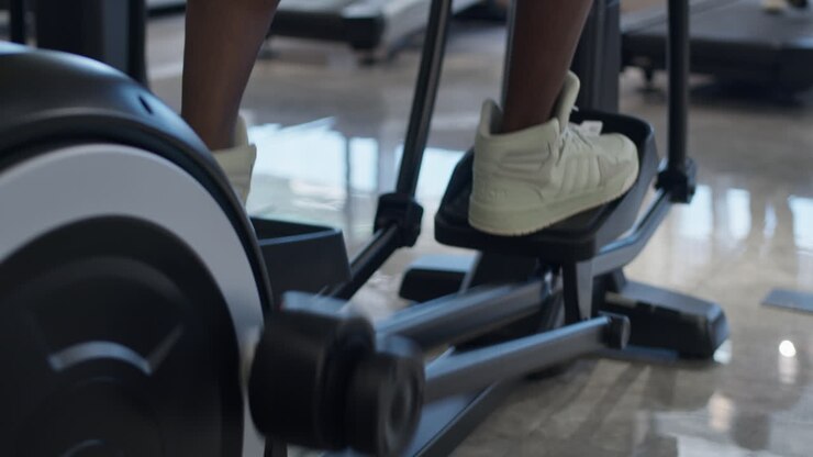 Person Exercising on a Cross-Trainer in a Gym