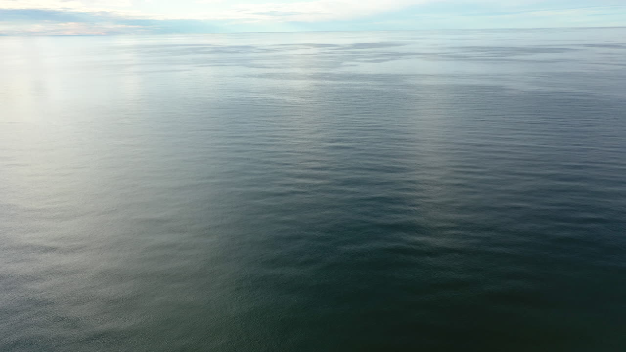 AERIAL: Rotating Shot of Vast Ocean with Blue Sky Horizon
