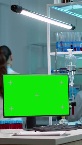 vertical video: chemists working in background of lab using pc with green screen