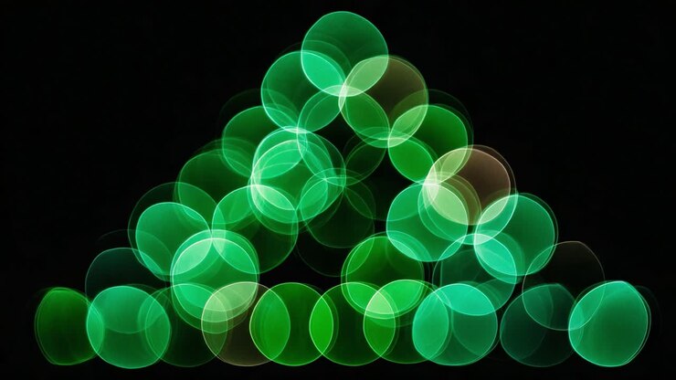 Vivace esposizione di forme bokeh verdi che creano un motivo triangolare con messa a fuoco morbida ed estetica sognante su sfondo scuro
