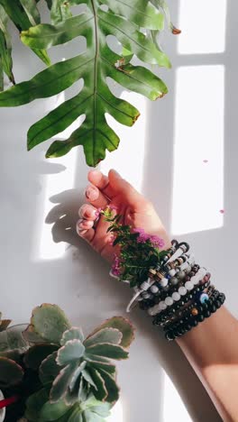 hand with bracelets and flowers among plants