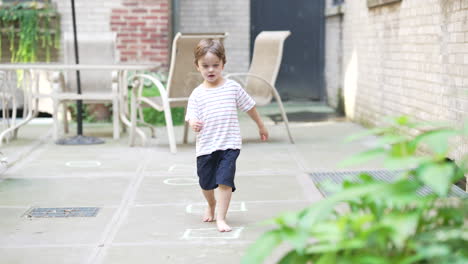 one isolated american blonde kid playing barefoot in the backyard