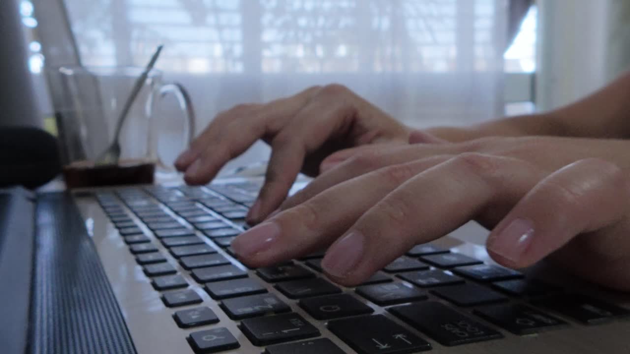 Side view highlighting female hand position and ergonomics while typing on a laptop