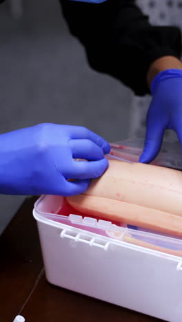 practical lesson with an injection. practitioner doing a training injection into a vein on a dummy. procedure of pricking into manikin arm. close-up. vertical video
