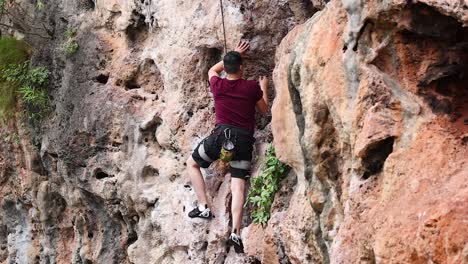 climber ascends rocky cliff at railay beach