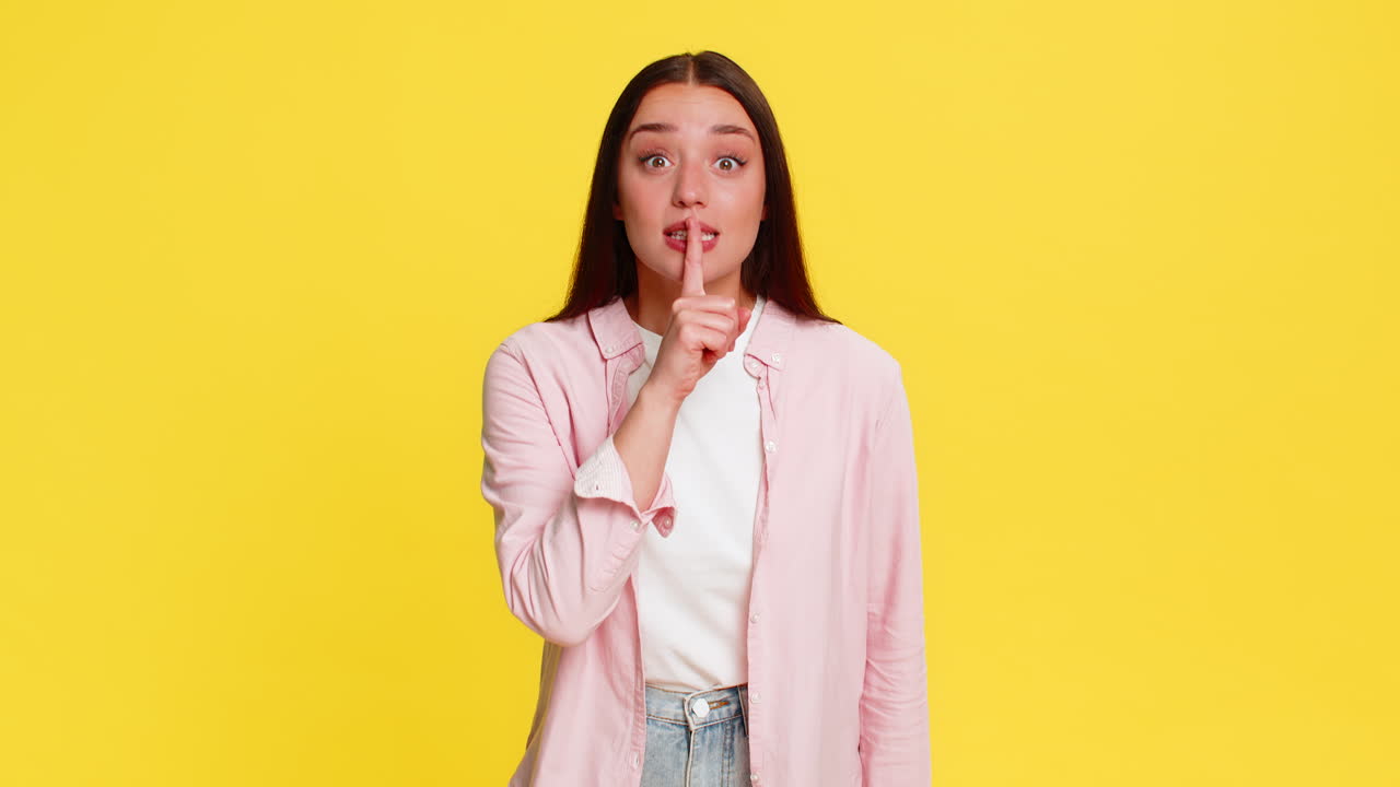 Woman placing finger on lips showing silence gesture asking for quiet serious thoughtful expression