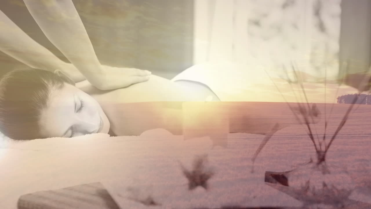 등 마사지를 받으며, 해가 지는 동안 평온한 해변 풍경에서 휴식을 취하는 여성