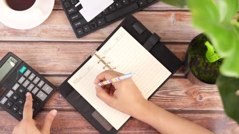 persona que toma notas y hace cálculos en un escritorio