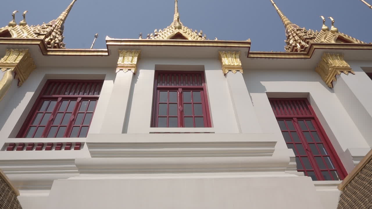 Slow motion clip dolly in and out  of the outside of a popular tourist attraction white and gold buddhist temple in the city of Bangkok in Thailand