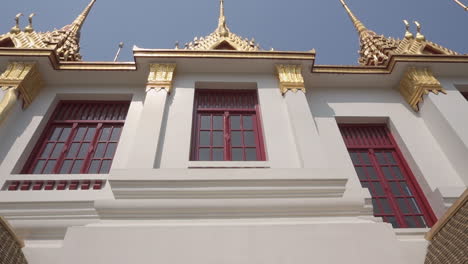slow motion clip dolly in and out  of the outside of a popular tourist attraction white and gold buddhist temple in the city of bangkok in thailand