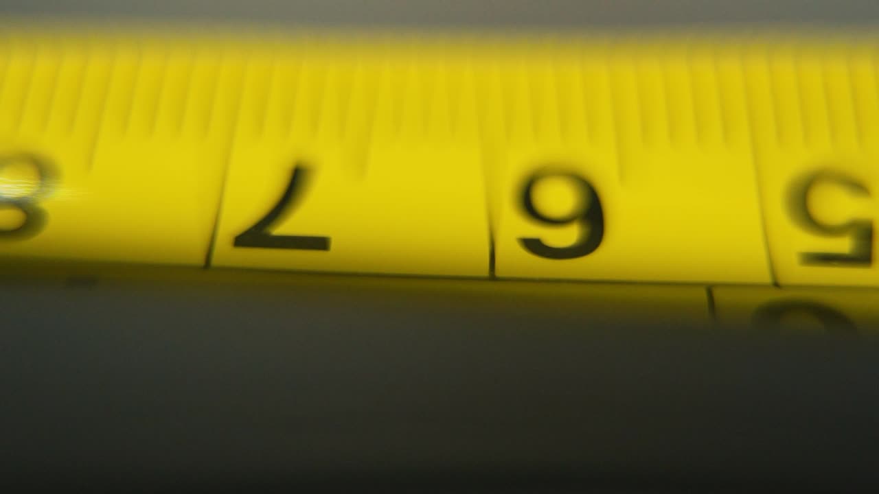 macro video de un medidor amarillo, herramienta de medición, súper primer plano, cámara lenta 120 fps, full hd, deslizamiento derecho movimiento de la grúa