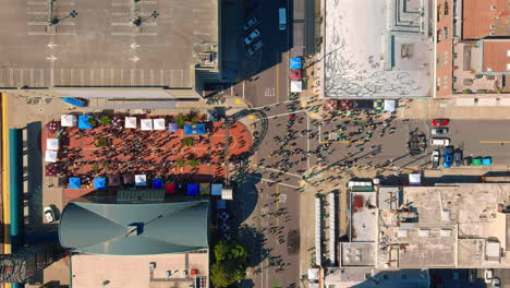 Bird's-eye-view-of-Athletics-Fan-Fest-in-Oakland-with-crowds-and-colorful-stalls,-sunny-day,-timelapse