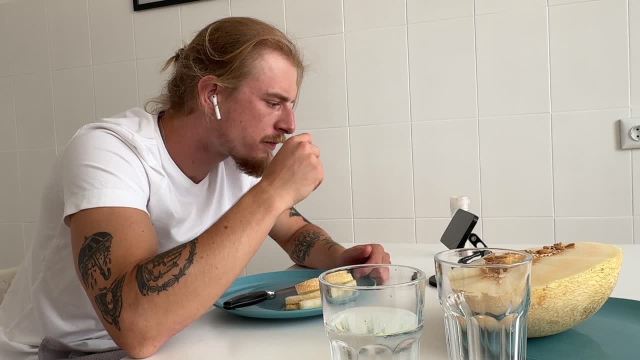 Hombre joven comiendo queso y pan para desayunar en la cocina