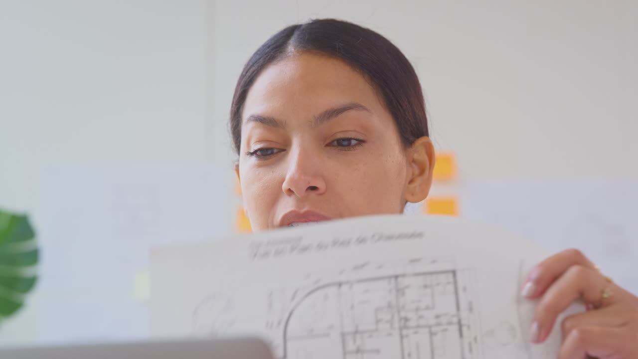 arquitecta femenina con computadora portátil en la oficina sentada en el escritorio mostrando planes para un nuevo edificio en una llamada de video