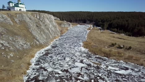 river with ice floes and church on cliff