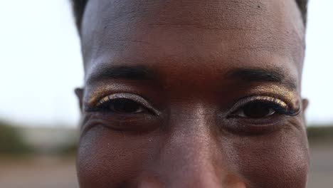 happy gay african man with make-up smiling on camera outdoor