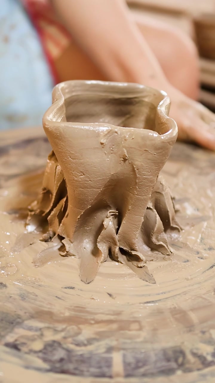 Primo piano di mani che modellano argilla umida in un vaso decorativo in un laboratorio tradizionale