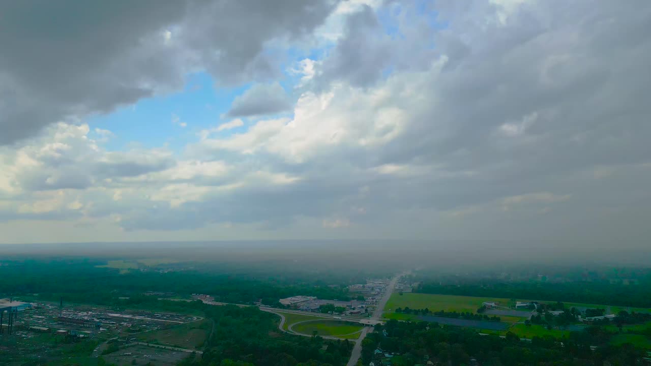 vista aérea de un espectacular cielo nublado que se asoma sobre un paisaje industrial, capturando el contraste entre la naturaleza y el desarrollo urbano