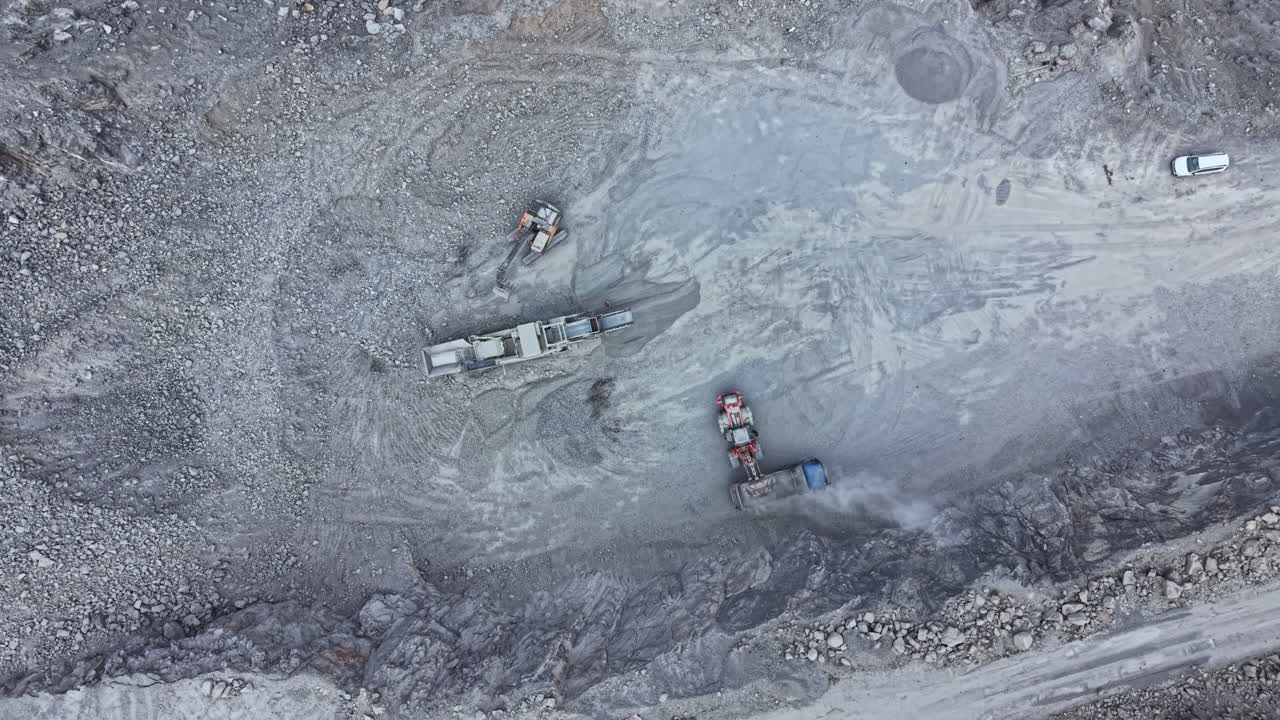 Construction vehicles work on a gravel site in a large quarry while preparing the ground for future projects
